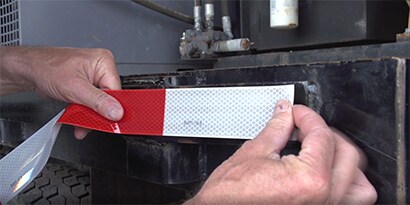 Applying reflective tape to truck
