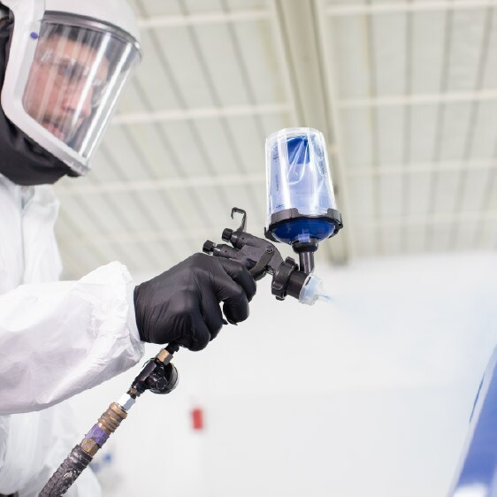 Mano con guante colocando un disco de lija morado en una lijadora orbital, con chispas al fondo en un entorno de taller.