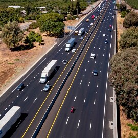 A close-up view of a tire driving past a white pavement marking on a highway.