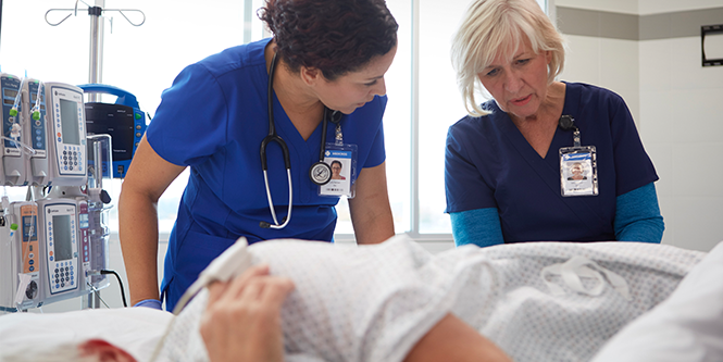 Two clinicans assessing a patients pressure injury
