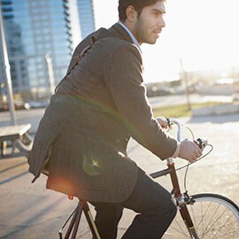 Man wearing blazer and riding bicycle in urban area.