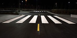 Highly visible pavement markings, including crosswalk and lane dividing line, at night.
