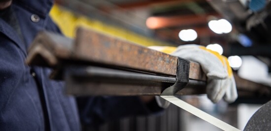 A worker bundling metal rods using black 3M™ DT Series Duct Tape.
