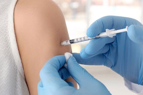 Patient receiving shot in arm from doctor