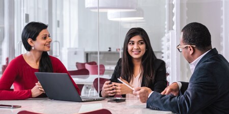 Three people sitting around a table reviewing documents.
