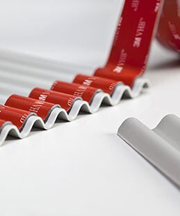 Image of 3M™ VHB™ Tape being applied to a sheet of corrugated metal