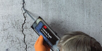 Person using 3M™ Scotch-Weld™ Concrete Repair DP600 to crack in concrete.
