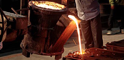 Fundición de metal caliente vertido en moldes en una planta industrial, mostrando el proceso de fabricación y producción de piezas metálicas.
