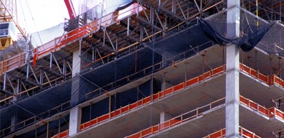 Tall building under construction with guardrails and netting around open floors
