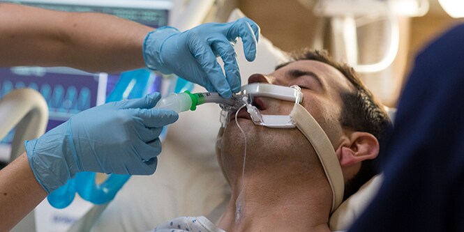 clinician adjusting breathing equipment on patient
